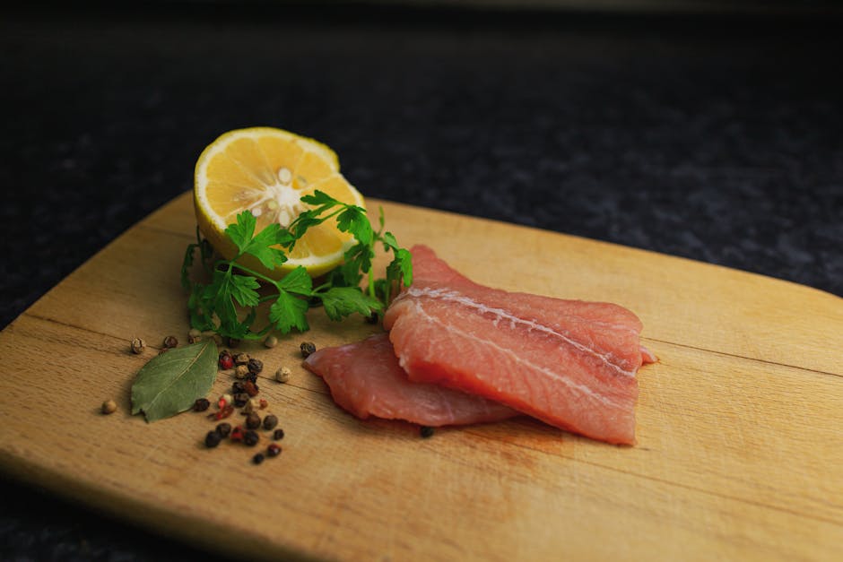 Raw salmon fillet with lemon, parsley, and spices on a wooden board. Ideal for food photography.